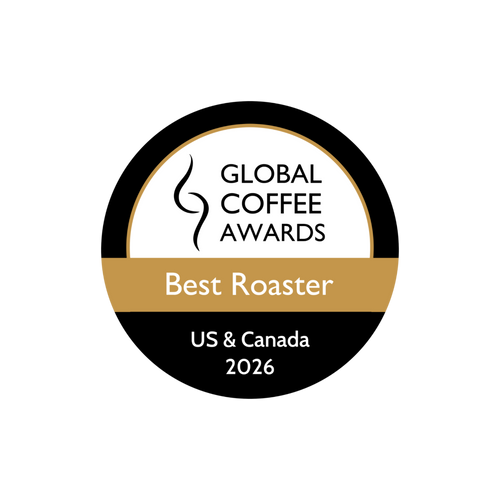 A circular award badge for the Global Coffee Awards Best Roaster 2026, US & Canada. The badge is black and white with a gold horizontal band across the center.