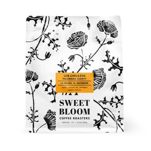 A bag of Sweet Bloom Coffee Roasters from Los Chelazos, featuring a white bag with black botanical illustrations and a central orange label.